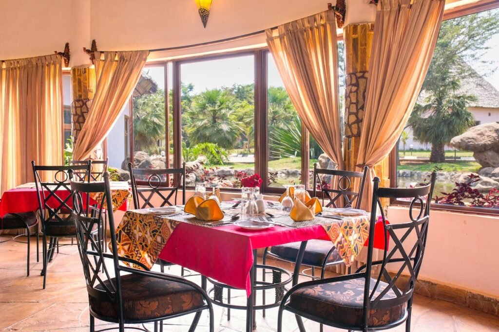 Dining tables beside windows looking onto the garden at Farm of Dreams Lodge, Karatu
